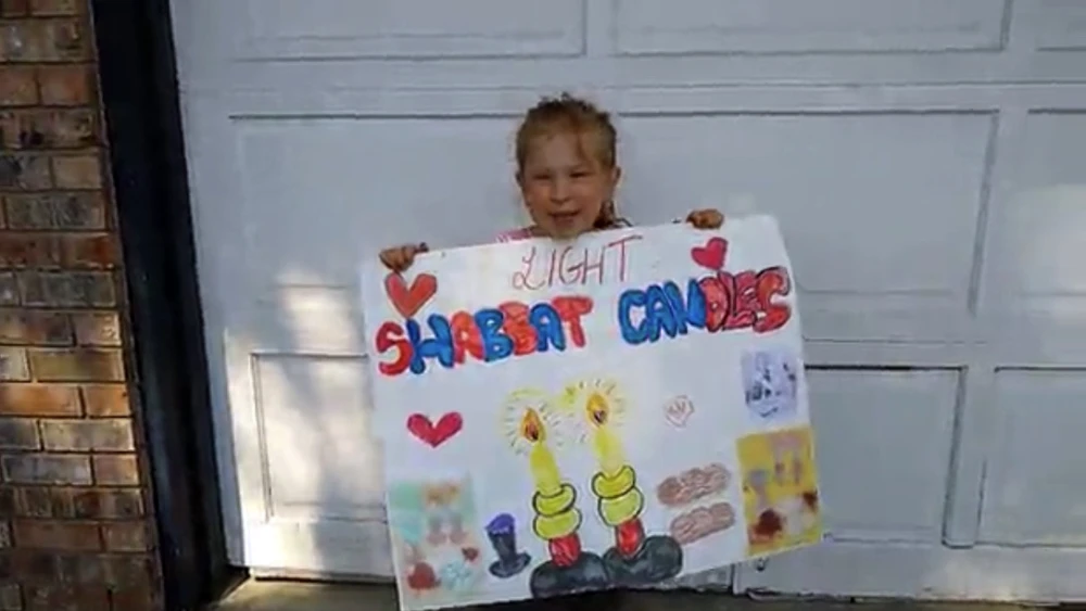 A child holds a poster to be part of a virtual Lag B’Omer parade organized by CKids, which it is dubbing “The Biggest Parade Ever.” Source: Screenshot.