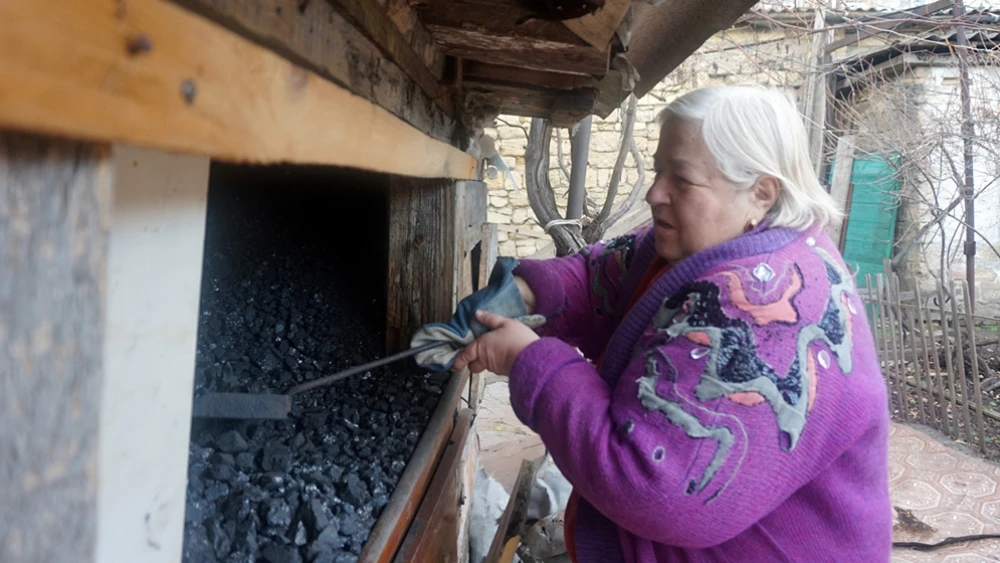 Nadezhda B. shovels coal provided to her by the American Jewish Joint Distribution Committee and the JDC-supported Hesed Social Welfare Center outside Odessa, Ukraine. Credit: JDC.