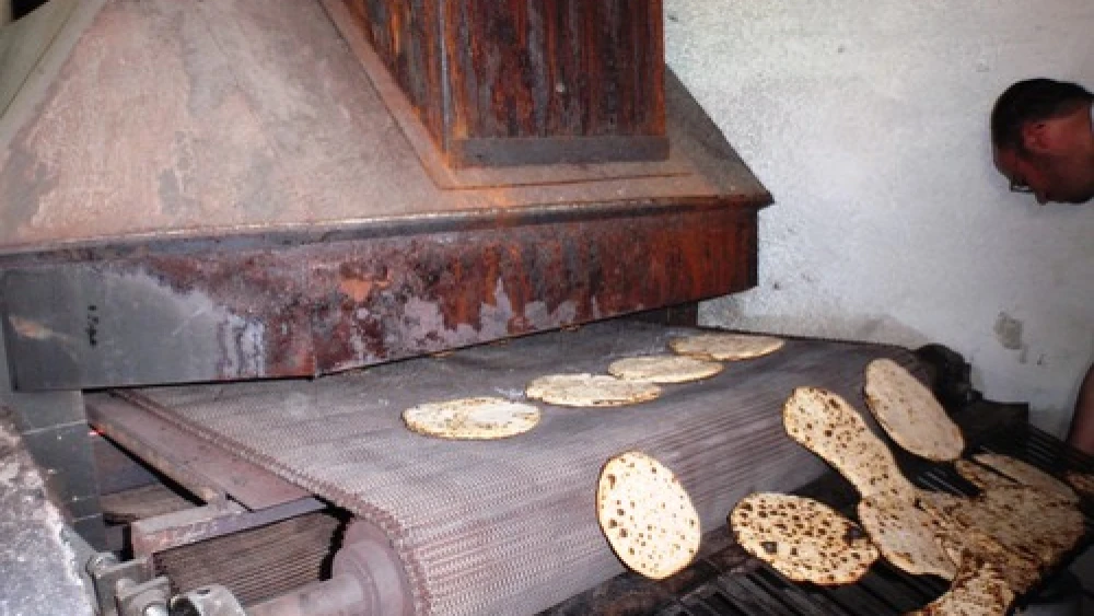 Handmade matzah comes out of the oven. Credit: Ariel Palmon via Wikimedia Commons.