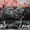 An Iranian man walks past an anti-U.S. billboard at Enghelab Square in central Tehran on Aug. 3, 2026, as Iran denies holding new negotiations with the United States to end the six-month war sparked by surprise U.S. and Israeli strikes on Feb. 28. Photo by Atta Kenare/AFP via Getty Images.