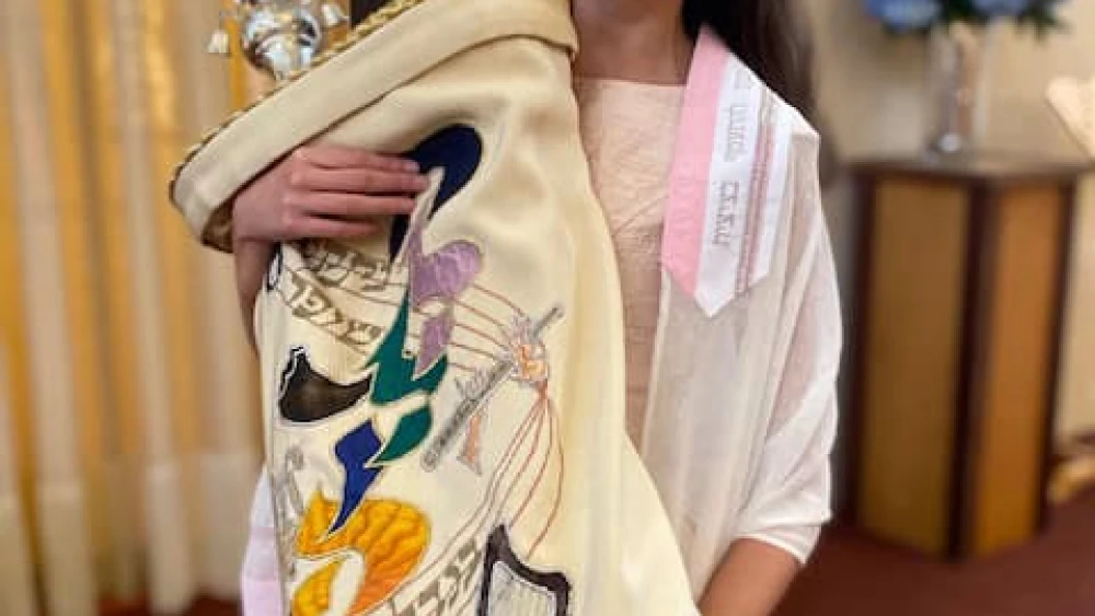 A young JBI patron with vision impairment happily celebrates while holding a Torah. Credit: Courtesy.