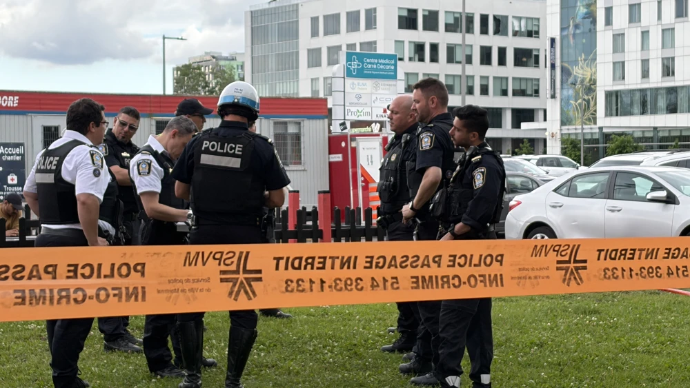 Damaged windows can be seen in the distance (top C) as police gather near the scene of a shooting in Montreal on June 22, 2026, which left three people dead. Photo by Daphné Lemelin/AFP via Getty Images.
