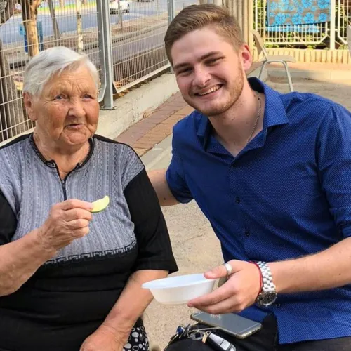 Yakov Pizenberg enjoys a snack with a senior citizen. Credit: Courtesy.