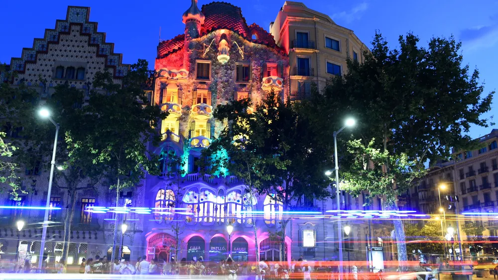 People gather as Spanish Catalan architect Antoni Gaudi's Casa Batllo is lit with the rainbow flag for Gay Pride month in Barcelona on June 28, 2019. Photo by JOSEP LAGO/AFP via Getty Images.