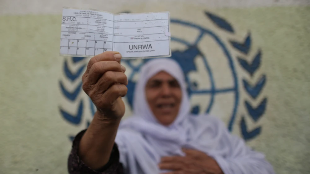 A Palestinian woman stands in front of UNRWA headquarters in Gaza City holding a refugee ration card during a protest demanding that the U.N. agency resume aid, April 8, 2013. Photo by Wissam Nassar/Flash90.