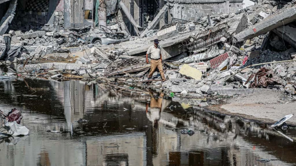 A man walks past destroyed buildings and sewage water erupting from collapsed underground pipes in Khan Younis, the southern Gaza Strip, July 8, 2024. Photo by Bashar Taleb/AFP via Getty Images.
