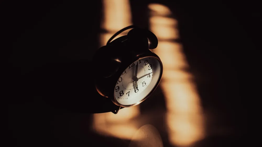 A clock sitting on a desk. Credit: Ruslan Sikunov/Pexels.