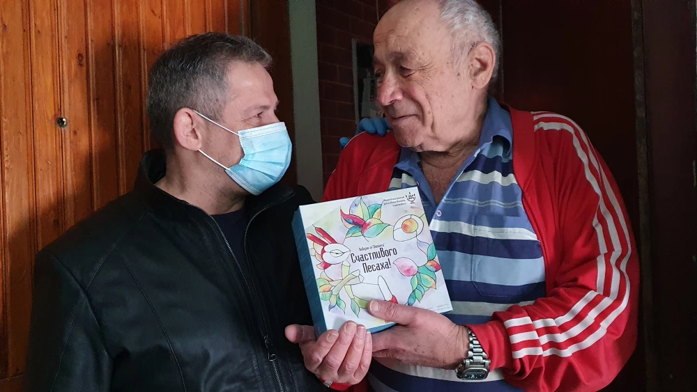 Anatoliy Shwartsman receives a box of matzah for Passover from a JDC worker. Credit: JDC.