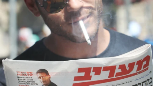 Israelis read about raised taxes on cigarettes and beer back on July 26, 2012. Photo by Miriam Alster/Flash90.