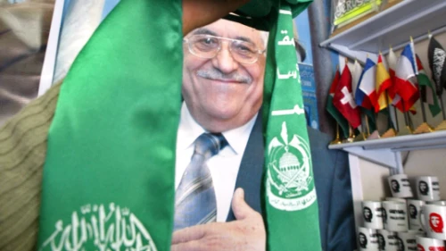 Gaza City, Gaza Strip on Feb. 7, 2006: Palestinian Abu Dayya holds up the Hamas flag in front of a poster of Mahmoud Abbas in his shop in Gaza City. Photo by Ahmad Khateib/Flash90.