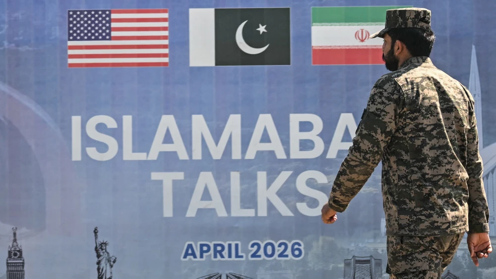 A Pakistani ranger walks past a billboard advertising U.S.-Iran peace talks in Islamabad on April 12, 2026. Photo by Farooq Naeem/AFP via Getty Images.