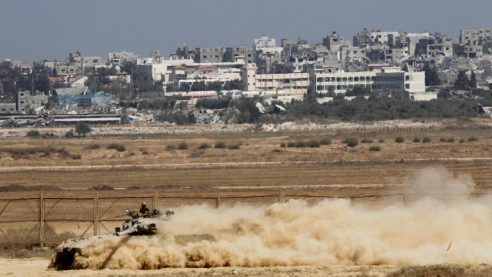 An Israeli Merkava tank moves along the border with Gaza (background), as Israeli forces prepare to clear the area, on Aug. 06, 2014. Photo by Miriam Alster/Flash90.