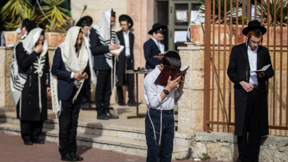 Jewish men pray outside a synagogue in the city Beitar Illit in the West Bank, March 29, 2020. Photo by Aharon Krohn/Flash90.