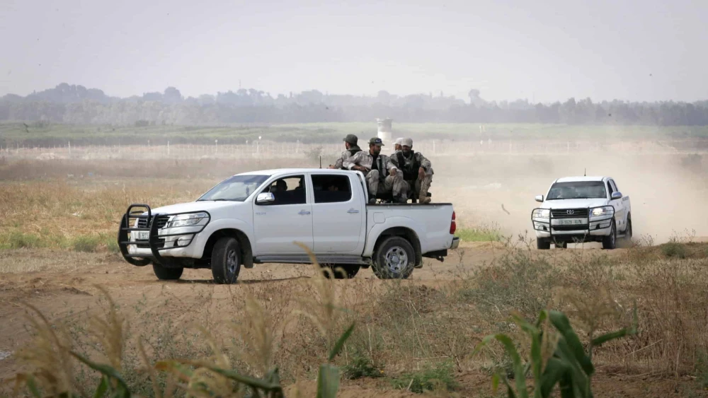 Palestinian terrorists of the Ezzedine al-Qassam Brigades, Hamas' armed wing, sit in the back of a pick-up truck watching Israeli bulldozers working along a barbed wire fence that separates Khan Yunis in the southern Gaza Strip and the Israeli border, on June 10, 2015. Photo by Abed Rahim Khatib/Flash 90.