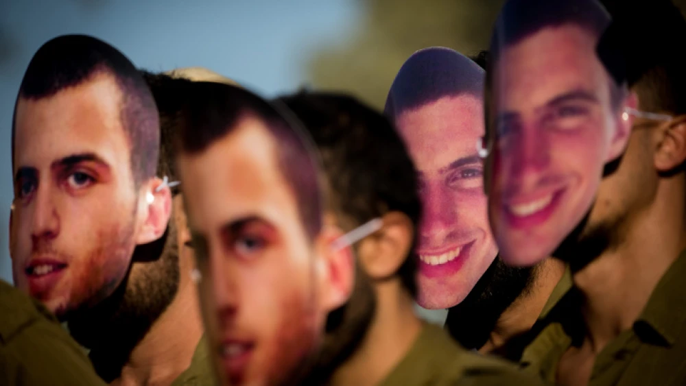 Friends of late Israeli soldiers Oron Shaul and Hadar Goldin wear masks portraying them as they protest for the release of their bodies, which are being held by Hamas in the Gaza Strip, outside the Knesset on July 1, 2020. Photo by Yonatan Sindel/Flash90.
