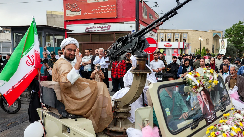 A Shia Muslim cleric groom rides with his bride in a military jeep, heading for a public mass wedding ceremony at Imam Hossein Square in Tehran, May 18, 2026. Photo by AFP via Getty Images. 
