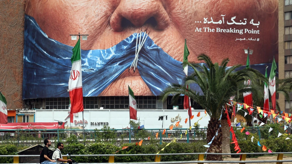 Iranians drive past a billboard featuring U.S. President Donald Trump and the Strait of Hormuz, on Valiasr Square in Tehran, May 28, 2026. Photo by AFP via Getty Images.