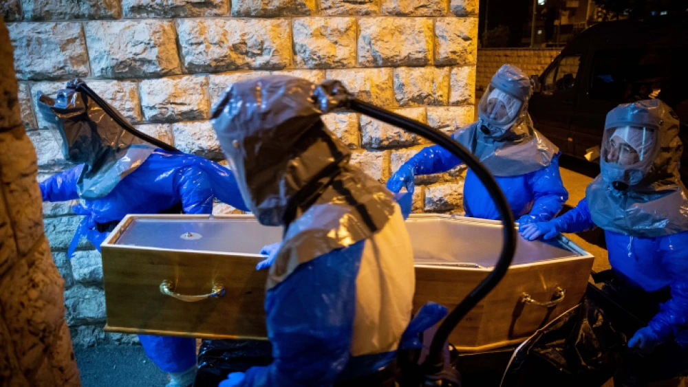 Chevra Kadisha workers wearing protective suits at the Shamgar Funeral Home in Jerusalem carry the body of a man who died of COVID-19 complications, March 24, 2020. Photo by Yonatan Sindel/Flash90.
