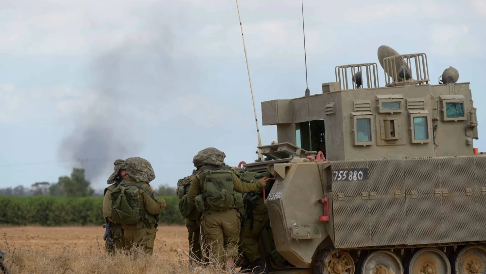 Israeli soldiers and armored vehicles are seen as smoke rises in the background near Kibbutz Sufa on the Gaza border, July 17, 2014. Photo by Gili Yaari/Flash90.