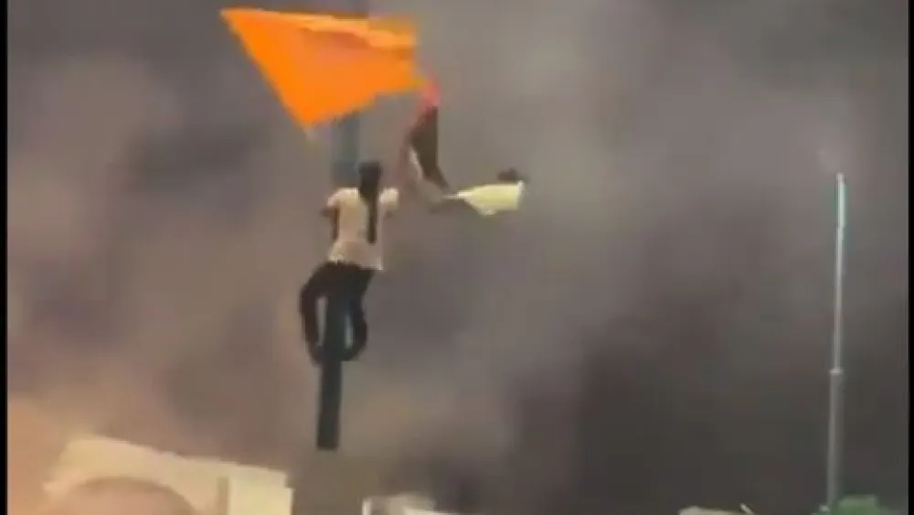 An Arab-Israeli Lod resident climbs up a pole to replace an Israeli flag with a Palestinian one, May 10, 2021. Source: Twitter/Screenshot.