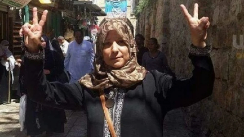 Click photo to download. Caption: Suhair Halabi flashes “V” for “Victory” signs with both hands at the site where her son, Muhannad, carried out a deadly terrorist attack. Credit: Facebook.