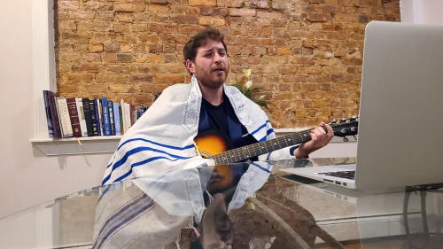 Levi Cohen at his computer as he sings melodies welcoming the onset of Shabbat. Credit: Dovid Zaklikowski.