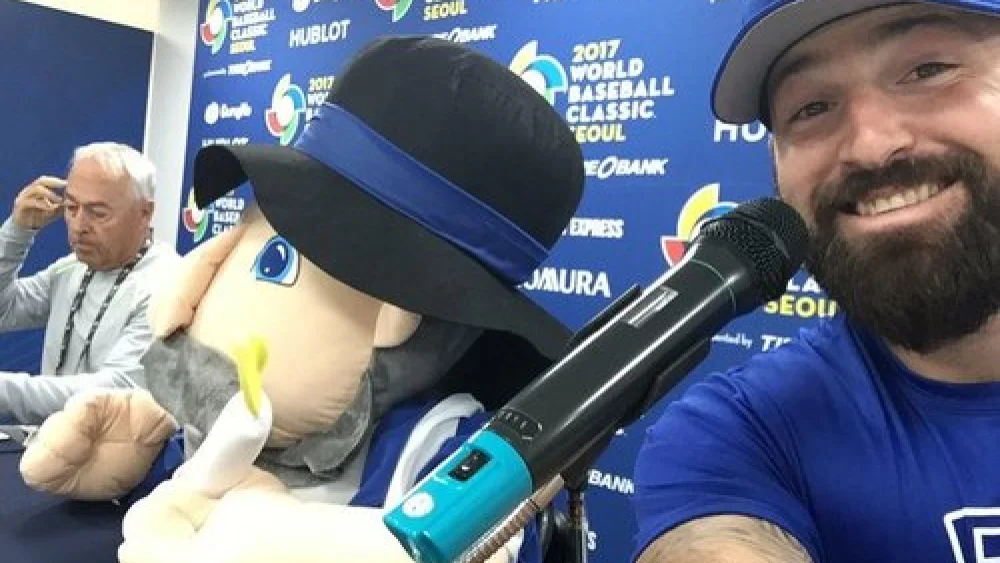 Cody Decker (right), a member of Team Israel at the World Baseball Classic (WBC), poses with the Israeli team’s mascot—the Hanukkah toy Mensch on a Bench (center)—at a WBC press conference in March. Credit: Cody Decker via Twitter.