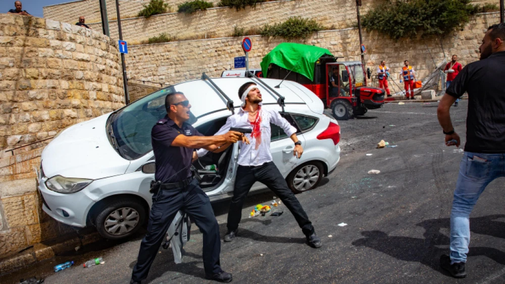 An Israeli policeman fends off an angry Arab mob swarming an Israeli motorist, pelting his car with stones and driving him off the road, outside Jerusalem's Old City, May 10, 2021. Photo by Olivier Fitoussi/Flash90.