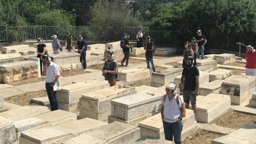 Participants take part in "Remote X" in a Jerusalem cemetery. The tour is based on a skeleton of a narrative in which the performers are “remoted” from the normal ways they interact with the city, experiencing it as a meta-reflection while walking the streets. Credit: Eliana Rudee.
