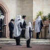 Jewish men pray outside a synagogue in the city of Beitar Illit in Judea and Samaria, on March 29, 2020. Photo by Aharon Krohn/Flash90.