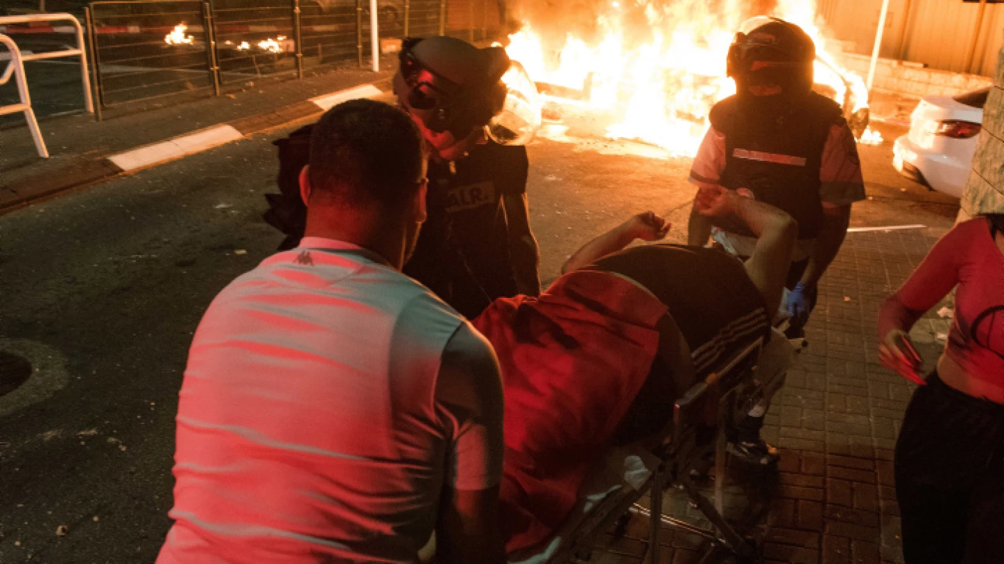 Israeli medics evacuate an injured man during Arab-Jewish riots in Akko on May 12, 2021. Photo by Roni Ofer/Flash90.