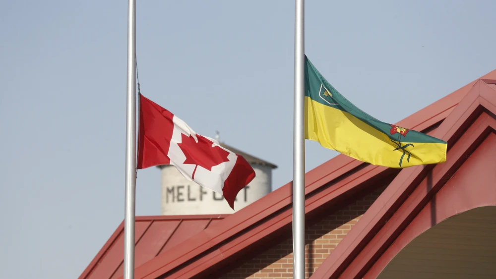 The Canadian flag and provincial flag of Saskatchewan fly at half mast at City Hall in Melfort, Saskatchewan, Canada, on Sept. 7, 2022. Photo by Lars Hagberg/AFP via Getty Images.