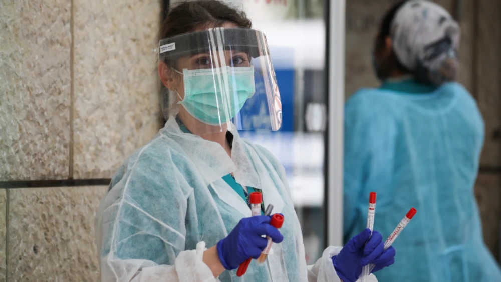 A health-care worker handes coronavirus test samples at Hadassah Ein Karem hospital in Jerusalem on March 26, 2020. Photo by Olivier Fitoussi/Flash90.