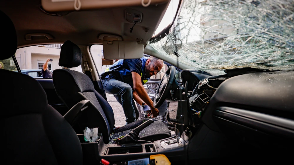 A policeman checks a car damaged by a Hezbollah rocket in Kiryat Bialik, Sept. 22, 2024. Photo by Chaim Goldberg/Flash90.