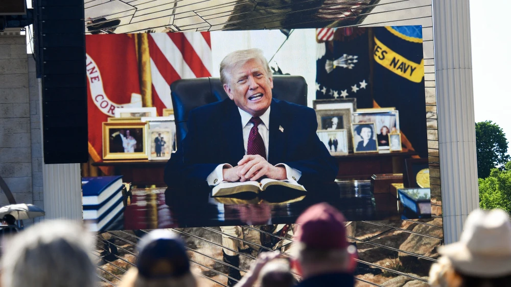 Attendees watch a pre-recorded video of U.S. President Donald Trump reading from the Bible during "Rededicate 250: A National Jubilee of Prayer, Praise and Thanksgiving" on the National Mall in Washington, DC, on May 17, 2026. Photo by Matthew Hatcher / AFP via Getty Images.