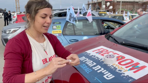 Israeli Freedom Convoy participant Efrat Fenigson decorates a car with protest flyers, Feb. 19, 2022. Photo by Orit Arfa.