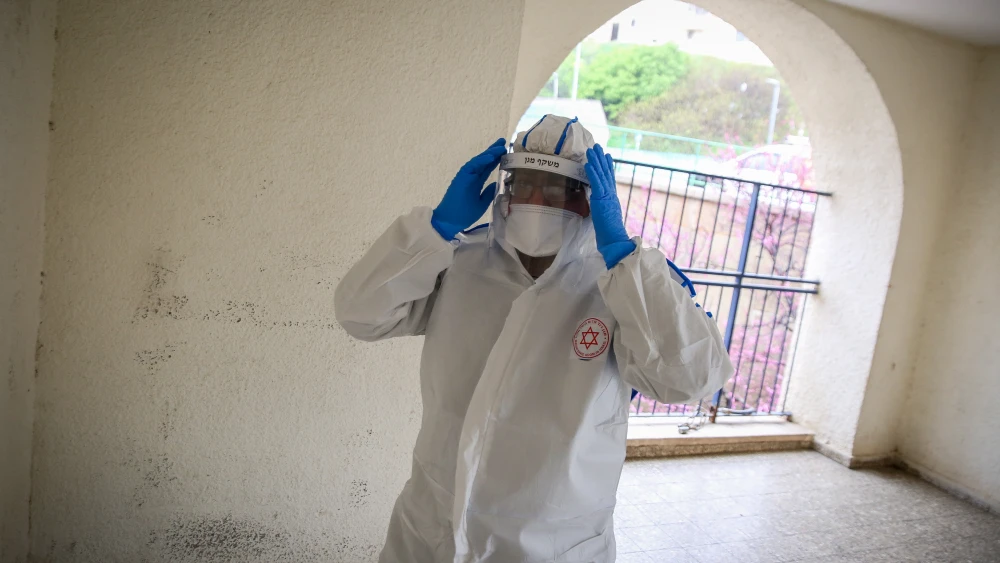 A Magen David Adom worker wearing protective clothing as a preventive measure against the coronavirus arrives to test a patient with symptoms of the coronavirus) in the northern Israeli city of Tzfat, March 17, 2020. Photo by David Cohen/Flash90.