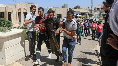A Bedouin tribal gunman is helped to a hospital in Izra, in Syria's southern Daraa Province, after being wounded in combat against Druze fighters in nearby Sweida on July 19, 2025. Photo by Abdulaziz Ketaz/AFP via Getty Images.