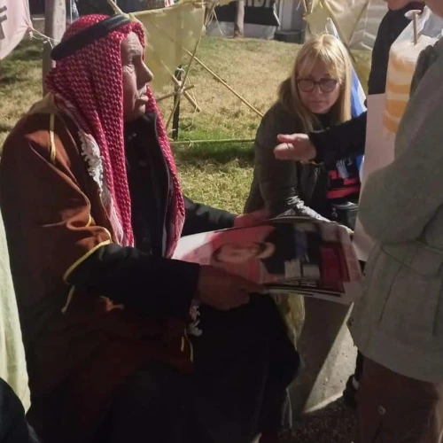 Sheikh Khaled, a resident of Rahat, shows pictures of relatives being held by Hamas in Gaza to supporters and other hostages' families at Tel Aviv's Hostage Square, on Feb. 10, 2024. Photo by Amelie Botbol.