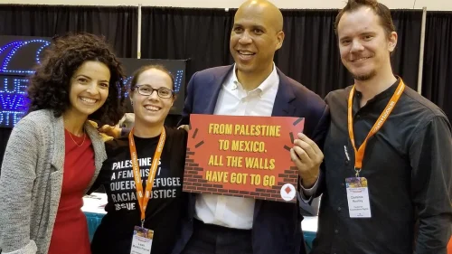 U.S. Sen. Cory Booker (D-N.J.) holds a sign reading: “From Palestine to Mexico, all the walls have got to go.” Credit: Twitter via U.S. Campaign for Palestinian Rights.