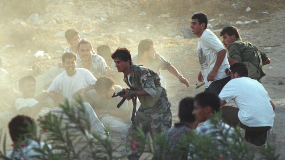 Palestinian gunmen take cover during an exchange of fire with Israeli soldiers in Ramallah on Sept. 25, 1996. Photo by Nati Shohat/Flash90.