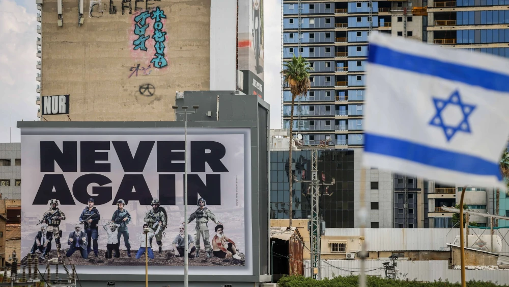 A large billboard with the words "Never Again" is seen above the Ayalon highway in Tel Aviv, Oct. 18, 2023. Photo by Chaim Goldberg/Flash90.