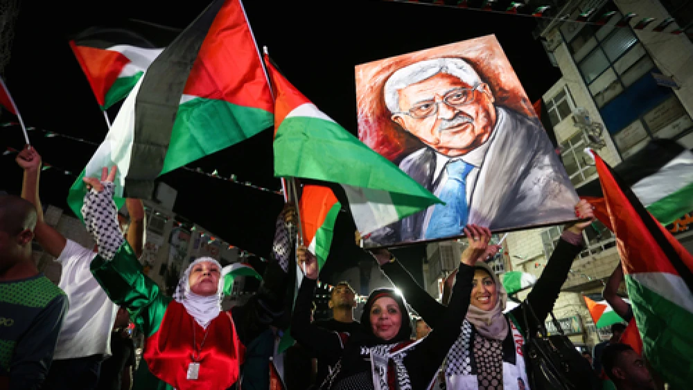 Palestinians in Ramallah wave their national flags and a picture of Palestinian Authority leader Mahmoud Abbas while they watch a live-screening of Abbas's speech at the United Nations, Sept. 30, 2015. Photo by Flash90.