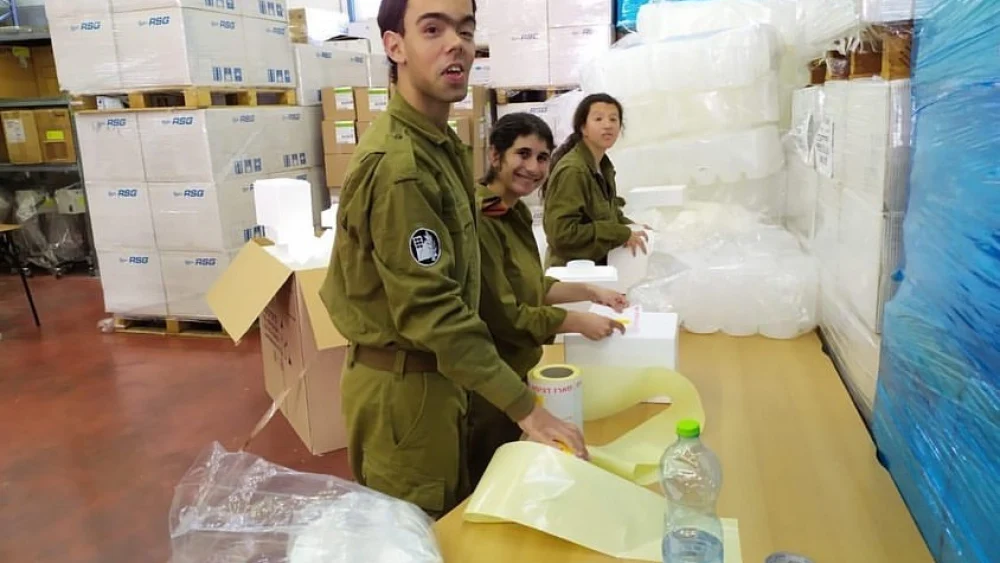 Soldiers in the Home Front Command, part of a volunteer program for soldiers with special needs, pack coronavirus testing kits as part of the national effort to combat the spread of COVID-19. Credit: IDF Spokesperson’s Unit.