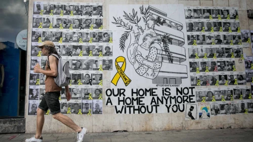 Israelis walk past a mural with photographs of Israelis held hostage by Hamas terrorists in the Gaza Strip since Oct. 7, in Tel Aviv, June 23, 2024. Photo by Miriam Alster/Flash90.