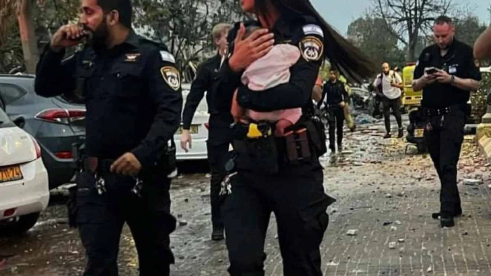 Police officer Staff Sgt. Aviv Saranga holding a three-month-old baby after she was pulled out of rubble in Rishon Letzion created by an Iranian ballistic missile strike on June 14, 2025. Photo by Dvir Mor/Israel Police.