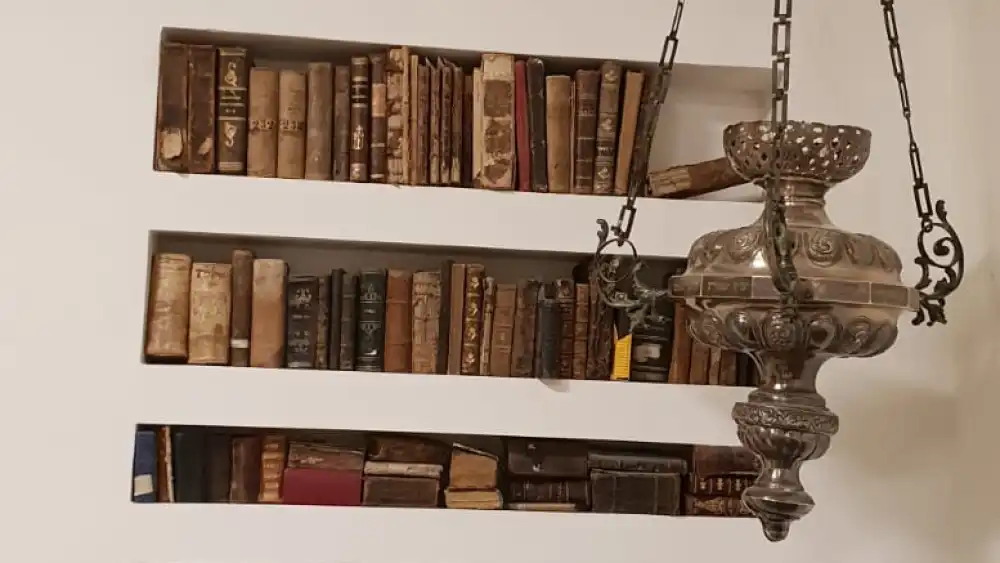 A collection of ancient Jewish books (sefarim) from around the world. The hanging lamp on the right is from a synagogue in Greece. The lions and tablets on top of the bookcase are from a synagogue in Uruguay by way of Hungary. Credit: Courtesy.