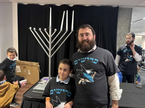 Rabbi Shaya Bernstein, co-director of the Chabad of Downtown San Jose, in front of a menorah at SAP Center in San Jose, Calif. Credit: Aaron Bandler.