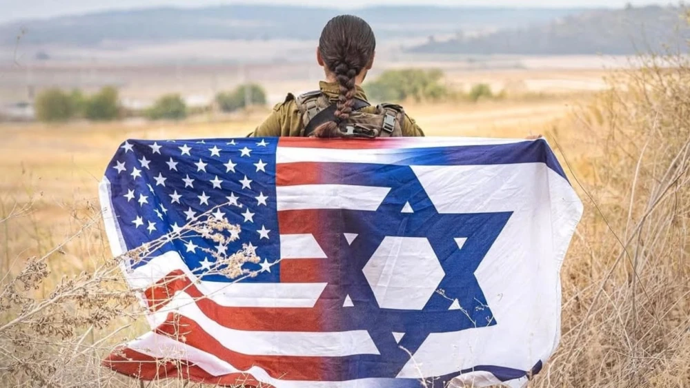 An Israeli soldier holds a combined U.S-Israeli flag ahead of Yom Ha'atzmaut, April 2026. Credit: IDF Spokesperson's Unit.