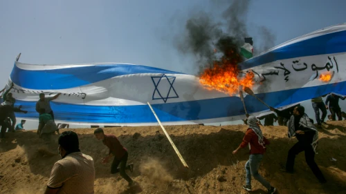 Palestinians protesters burn a a giant Israeli flag